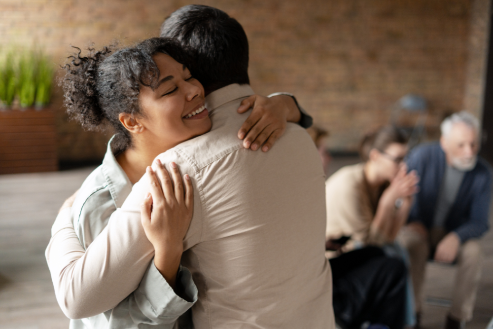 Woman hugging her coach after a therapy session, symbolizing support and positive connections in life after rehab.